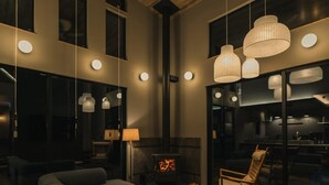 Un intérieur moderne avec une cheminée, des canapés et des luminaires suspendus.