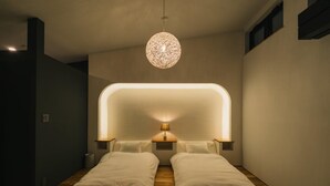 Une chambre dotée de deux lits, d’un luminaire au plafond original et d’un design moderne.
