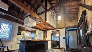 A spacious kitchen with a large island, wooden beams, and a checkered floor. - Akiya Cornerstone (Awaji)