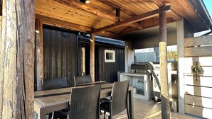 An outdoor patio with a wooden ceiling, a grill, and a dining table with chairs. - Akiya Cornerstone (Awaji)