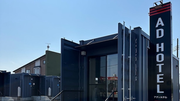 A modern hotel entrance with a glass door, a metal staircase, and a sign indicating the hotel name. - AD Hotel (Noshiro)