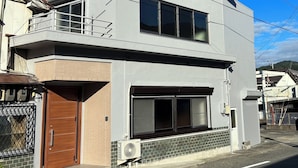 Ein modernes, zweistöckiges Gebäude mit Balkon, großen Fenstern und einer Klimaanlage.