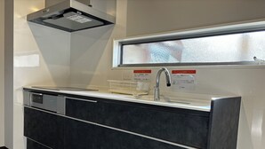Eine moderne Küche mit eingebautem Geschirrspüler, Edelstahl-Spüle und einem Fenster über der Spüle.
