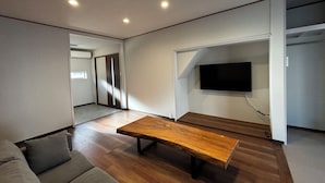 Ein modernes Wohnzimmer mit Couchtisch aus Holz, grauem Sofa und einem flachbildfernseher an der Wand.