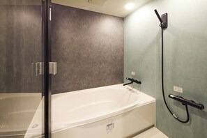 A modern bathroom with a bathtub, a glass shower enclosure, and a handheld showerhead. - Maigre Hoodstar (Ito)