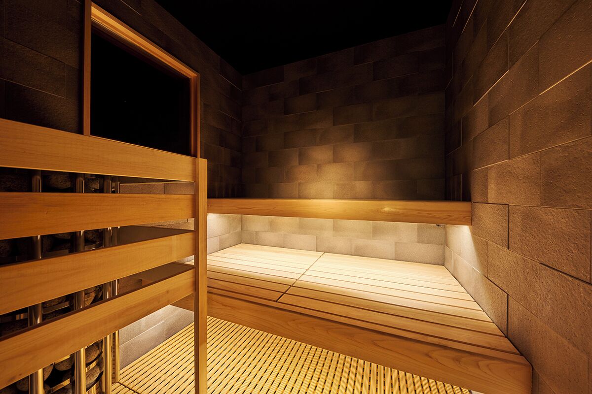 Un sauna avec des bancs en bois et un sol carrelé, entouré de murs en pierre.