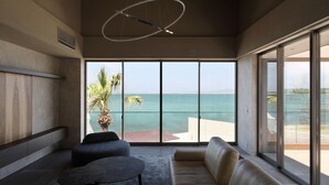 A modern living room with a large sliding glass door leading to a balcony with a view of the sea. - Lentement Suite-villa Awaji (Sumoto)