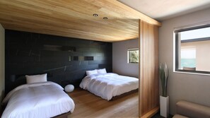 Quarto moderno com duas camas, uma parede de destaque escura, teto de madeira e uma grande janela com vista.