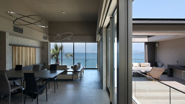 A modern interior with a dining area, a large window with a view of the sea, and a balcony with outdoor seating. - Lentement Suite-villa Awaji (Sumoto)