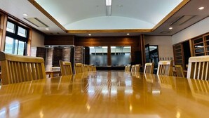 Ein Konferenzraum mit einem langen Tisch, Stühlen, Holzvertäfelung und großen Fenstern.
