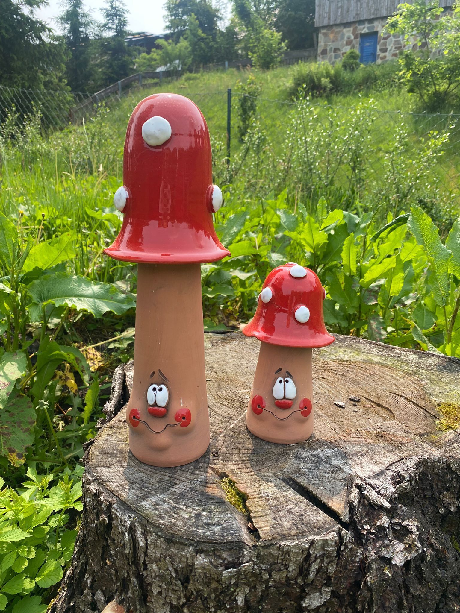 Two mushroom-shaped sculptures with faces on a tree stump.