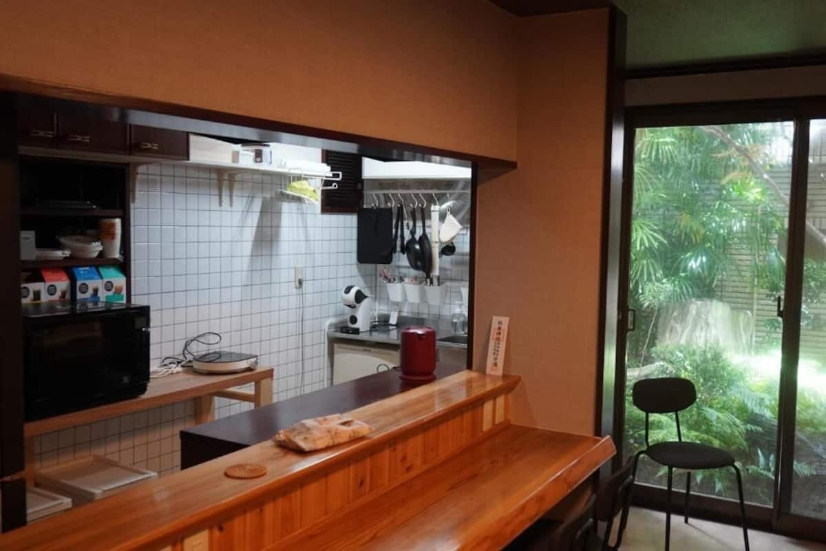 A kitchen with a wooden countertop, a sink, and a window with a view of greenery.