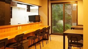 Un restaurant avec un comptoir, des chaises et une vue sur la verdure par la fenêtre.