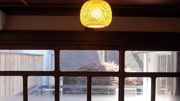 Une pièce dotée d’une grande fenêtre, d’une lampe suspendue et d’un bureau avec une lampe.