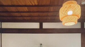 Une chambre avec deux lits en bois, un luminaire suspendu et une table de chevet avec une lampe.