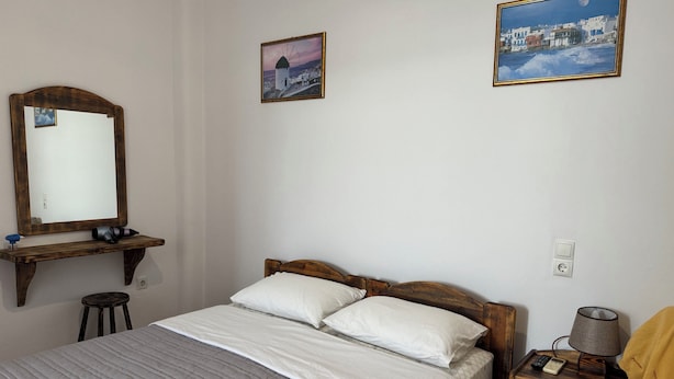 A bedroom with a bed, a nightstand, a lamp, and two framed pictures on the wall. - Anais Anais Mykonos (Mykonos)