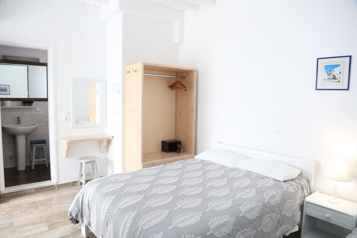 A bedroom with a bed, bedside table, and a wooden wardrobe.