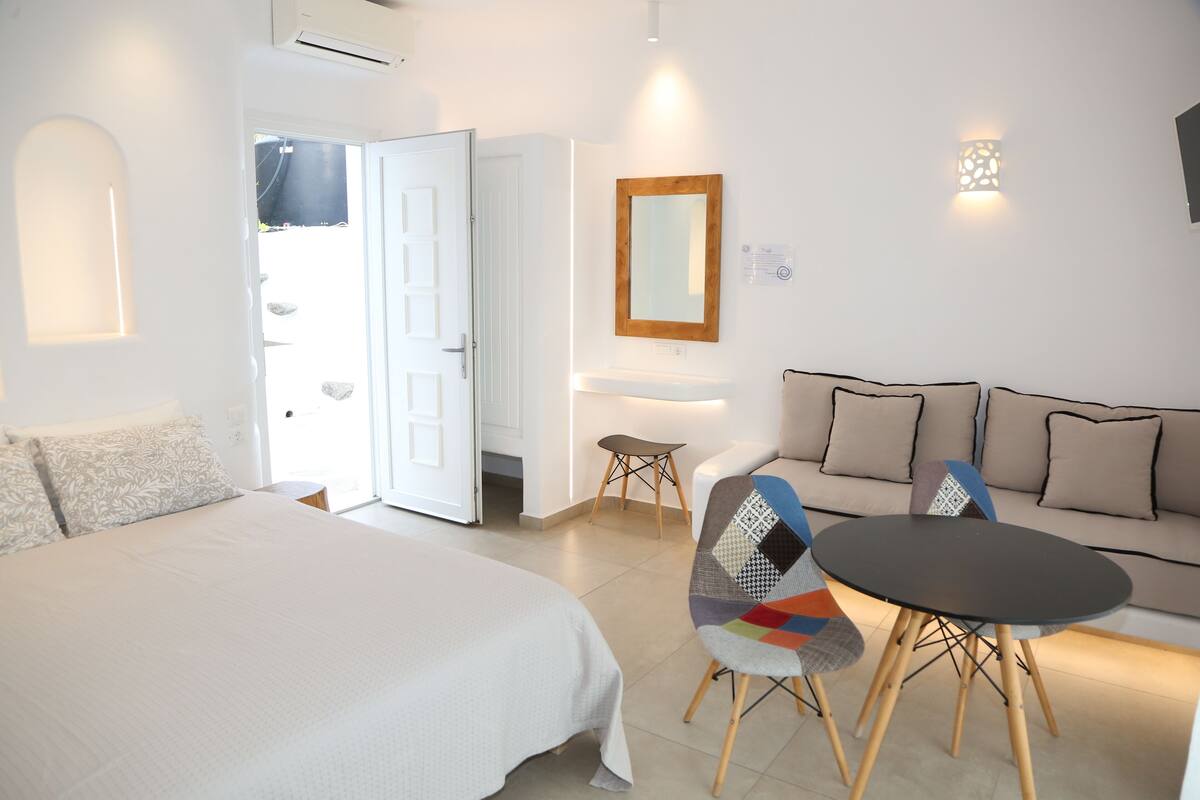 A bedroom with a bed, a sofa, a table, and a chair.