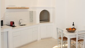 A modern kitchen with white cabinetry, a built-in oven, and a dining area with a table and chairs. - Anais Anais Mykonos (Mykonos)