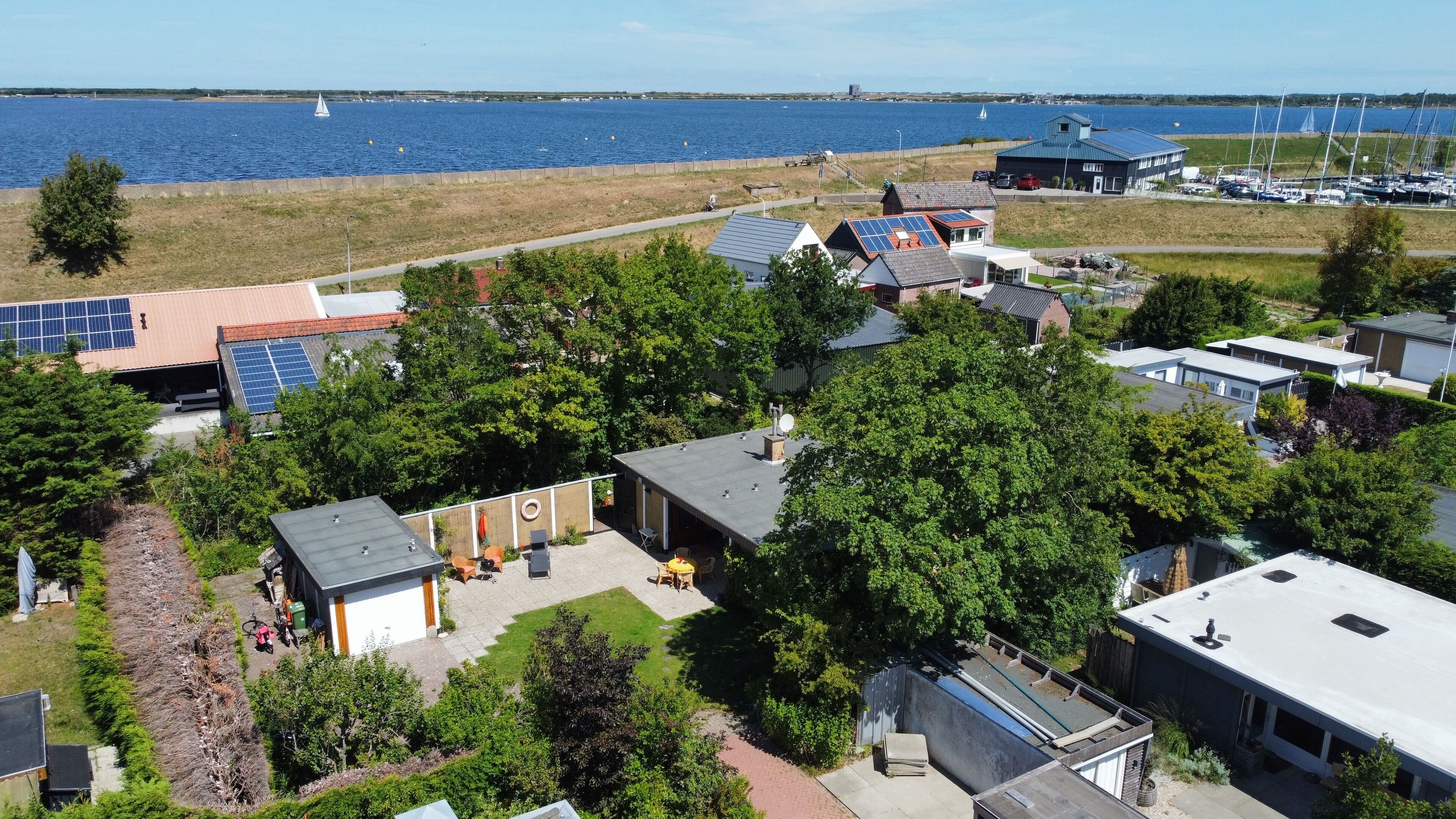 A residential area with houses, solar panels, and a marina with sailboats.