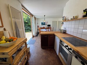 Eine Küche mit Holzausziehtisch, einem Einbauofen und einem Essbereich mit Tisch und Stühlen.