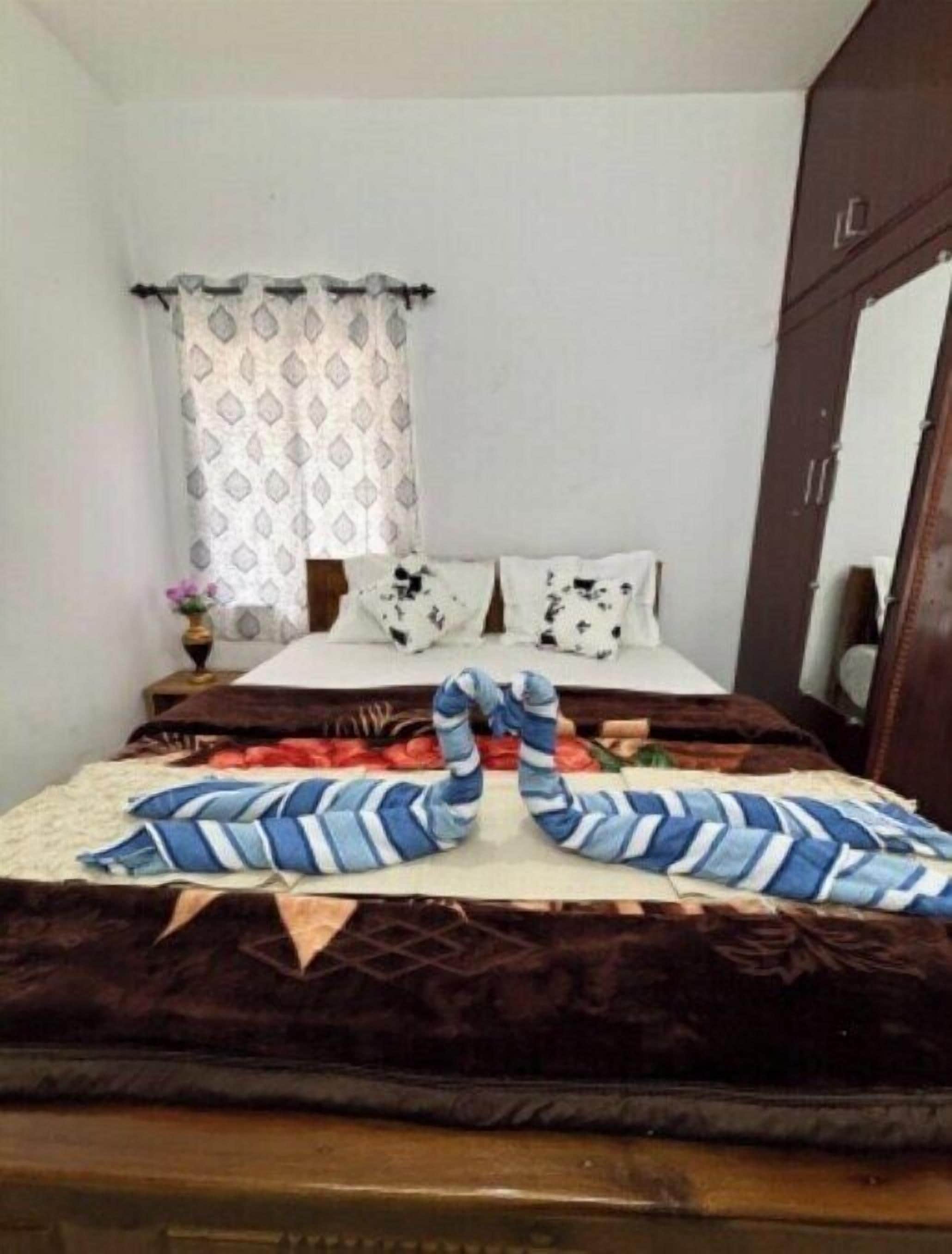 A bedroom with a bed, pillows, a curtain, and a blanket.