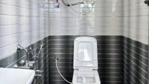 Une petite salle de bain comprenant des toilettes, un lavabo et un chauffe-eau fixé au mur.