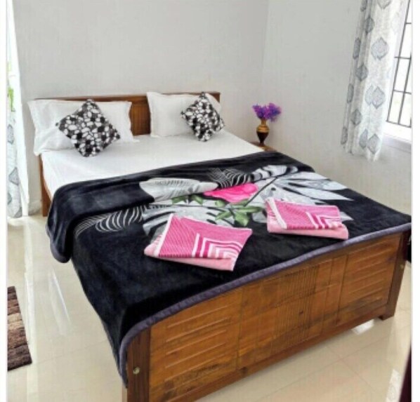 A bedroom with a wooden bed, white bedding, and a floral-patterned bedspread.