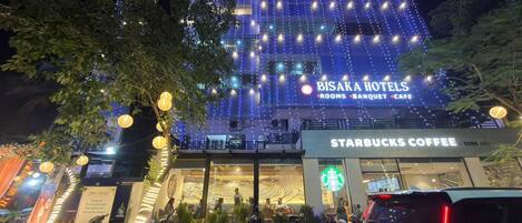 Egy hotel, amelyben Starbucks kávézó található, a belső térét pedig fényfüzérekkel díszítették, és számos motorparkolóhely is van a közelben.