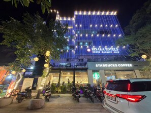 A hotel with a Starbucks Coffee, decorated with string lights, and several parked motorcycles. - Bisaka Hotel (Patna)