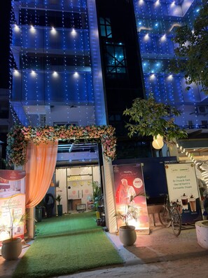 A hotel entrance with a green carpet, floral decorations, and string lights. - Bisaka Hotel (Patna)