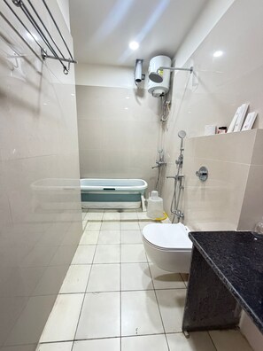 A bathroom with a bathtub, toilet, and shower area. - Bisaka Hotel (Patna)