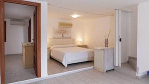A bedroom with a bed, bedside table, and a small cabinet. - Casa Leo by Wonderful Italy (Osseddu)