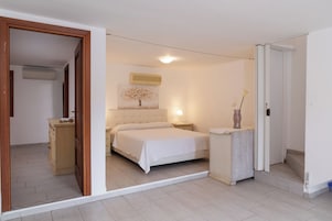Un dormitorio con cama, mesita de noche y un mueble pequeño.