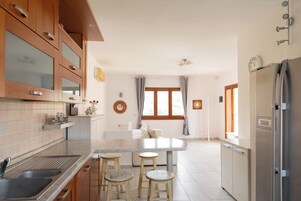 Una cocina moderna con armarios de madera, encimera de mármol y un lavamanos integrado. Hay tres taburetes en la isla de la cocina.