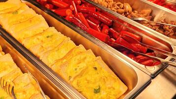 A buffet with various food options including omelets, red peppers, and fried chicken.