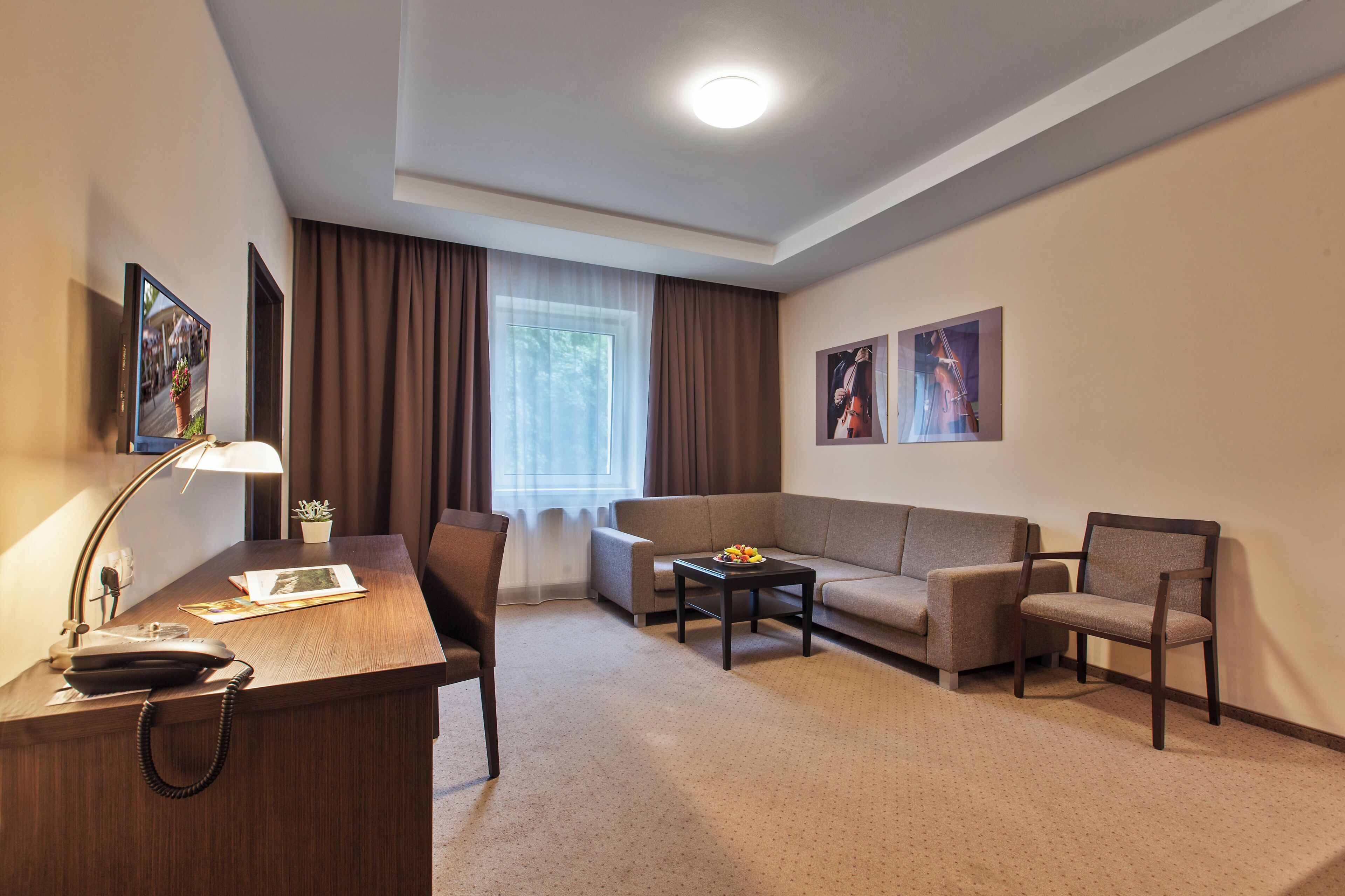 A hotel room with a desk, chair, sofa, and coffee table.