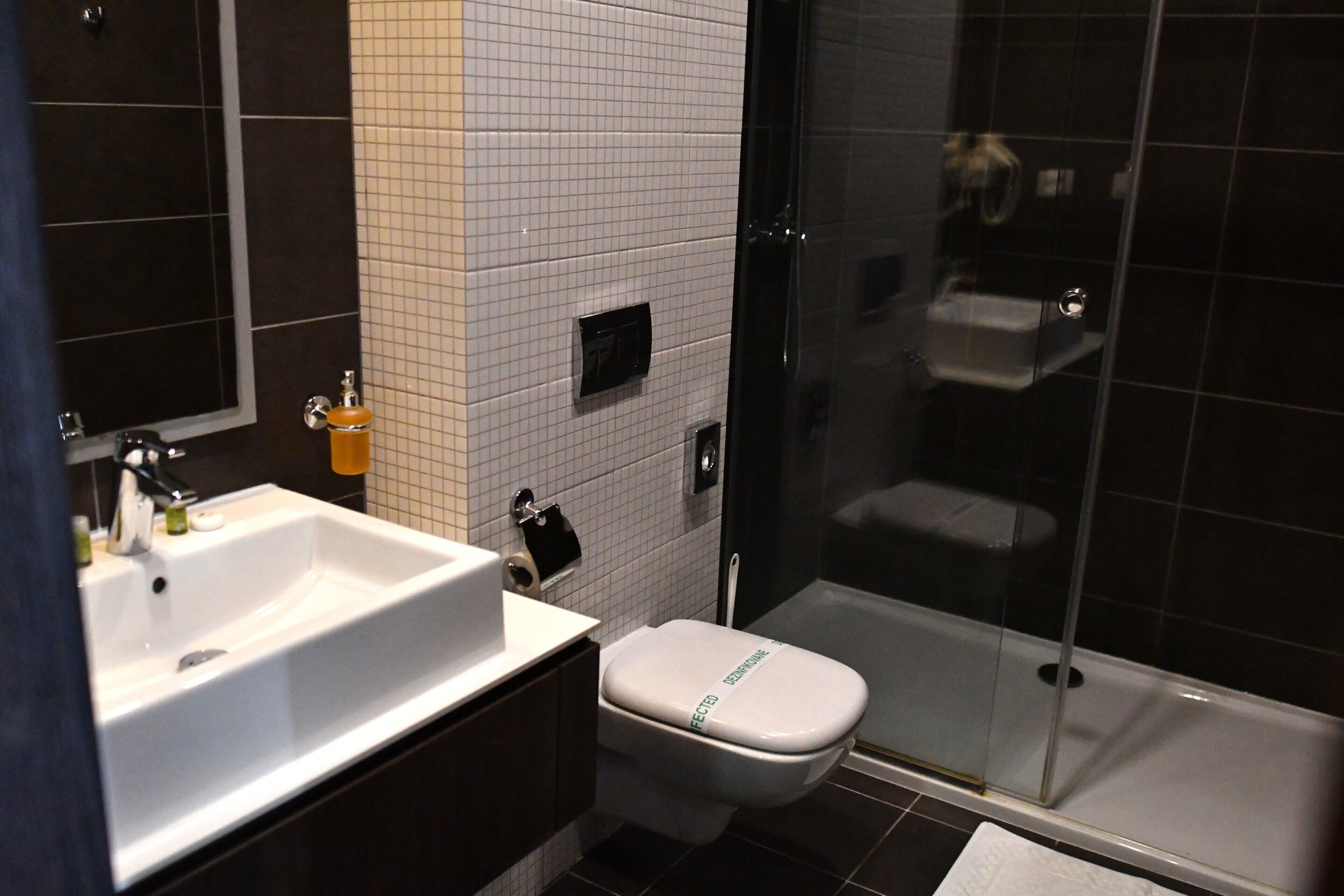 A bathroom with a white sink, toilet, and glass-enclosed shower.