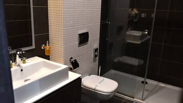 A bathroom with a white sink, toilet, and glass-enclosed shower.
