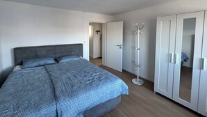 Een slaapkamer met een bed, een kledingkast en een kapstok.