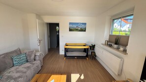 A small room with a bunk bed, a sofa, a window with a view, and a radiator.