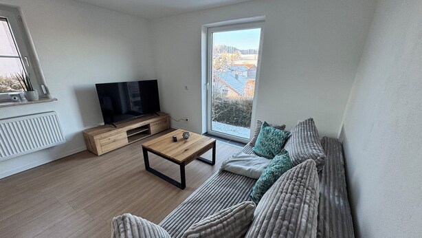 Een moderne woonkamer met een bank, salontafel en televisie.