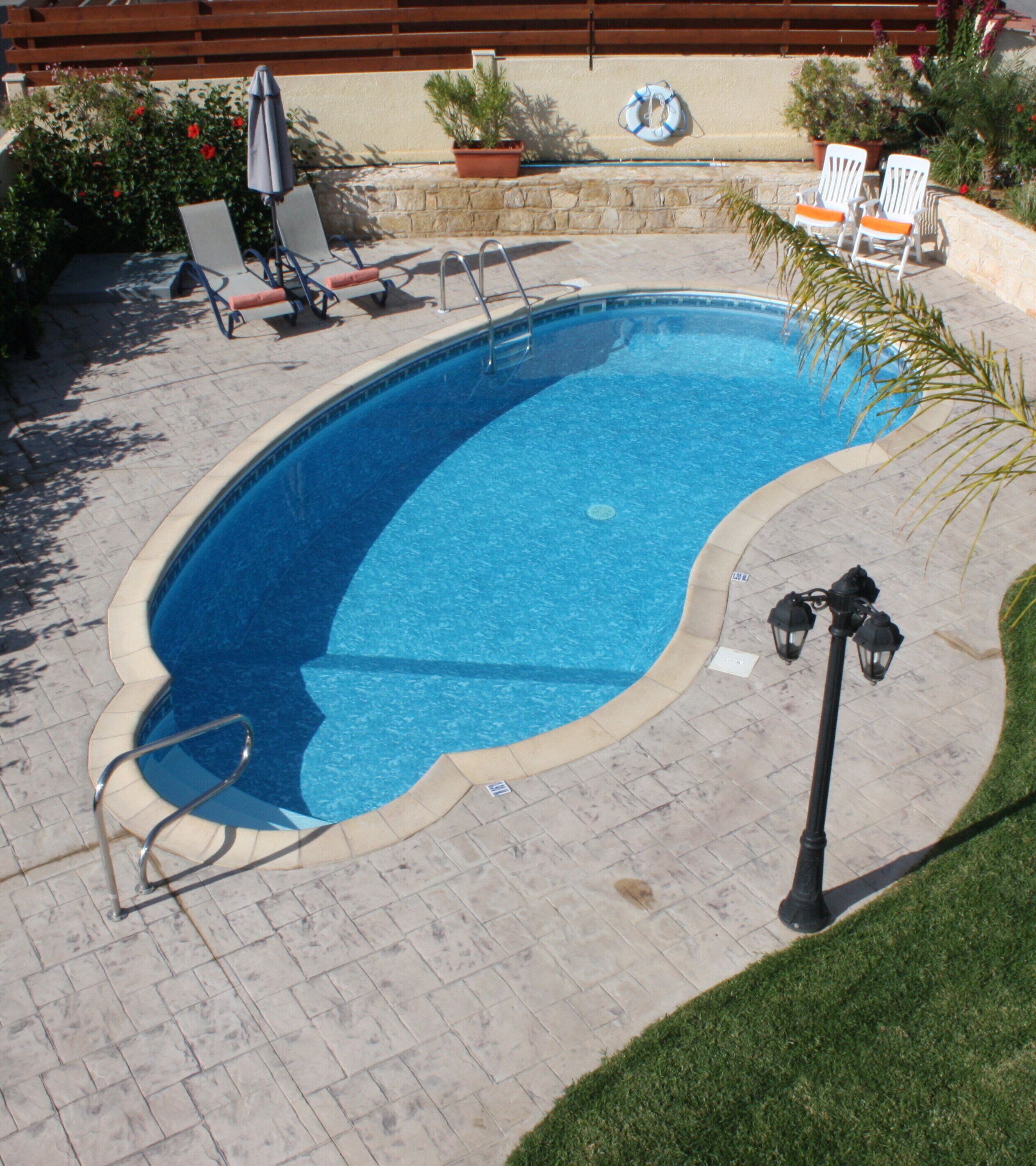 Una piscina con solárium empedrado, rodeada de sillones de descanso y un flotador salvavidas.