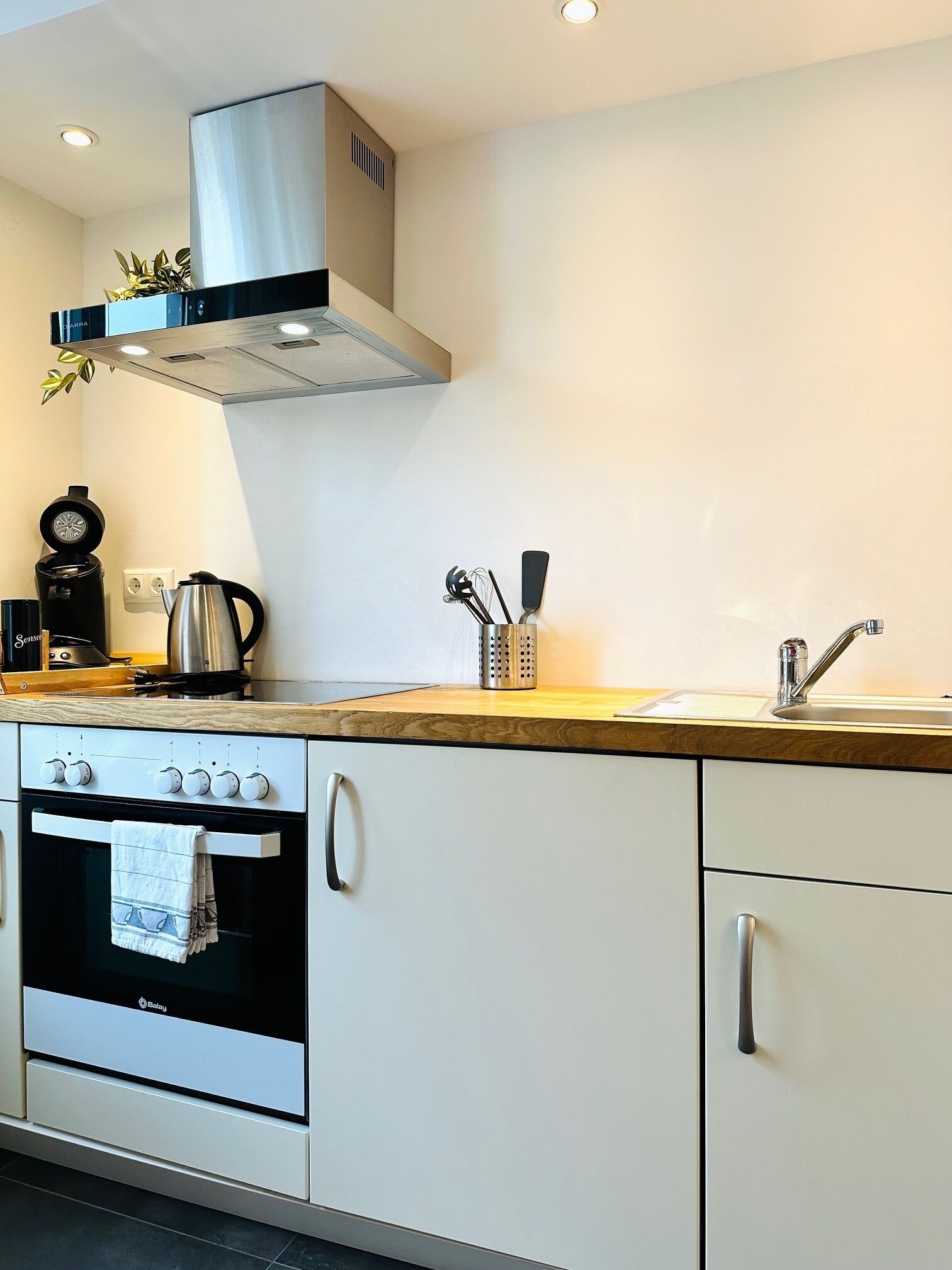 Een moderne keuken met een ingebouwde oven, een koffiezetapparaat en een waterkoker op het aanrecht.