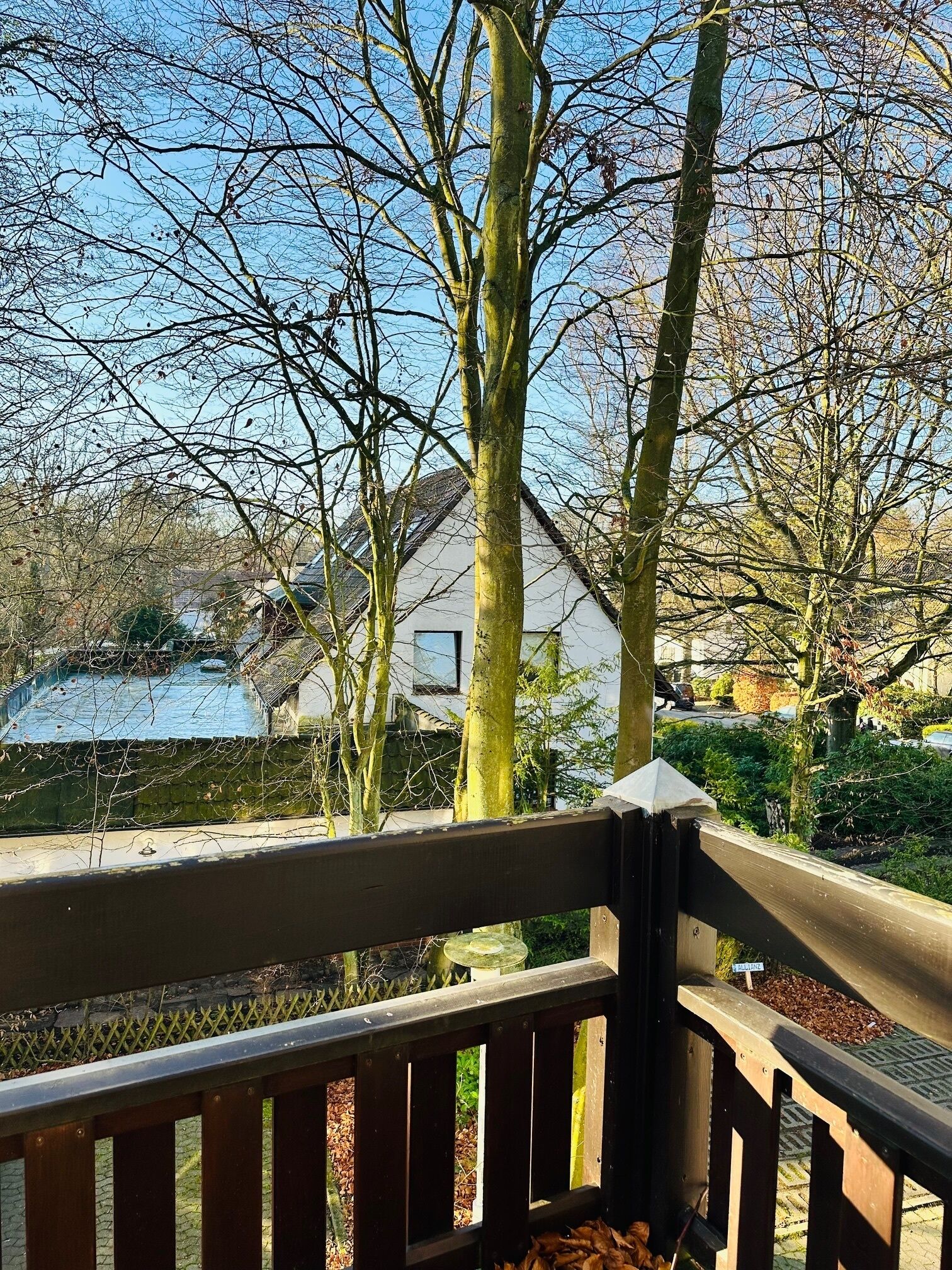 Une terrasse en bois offrant une vue sur une maison et un étang.