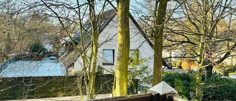 Une terrasse en bois offrant une vue sur une maison et un étang.