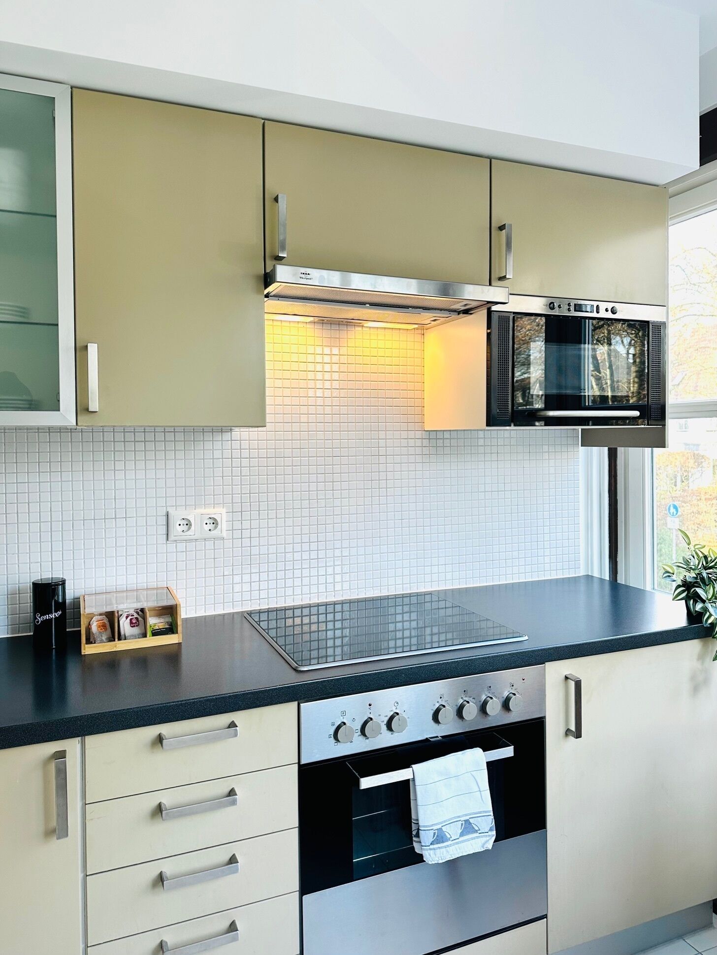 Una cocina moderna con horno empotrado, microondas y campana extractora sobre la estufa.