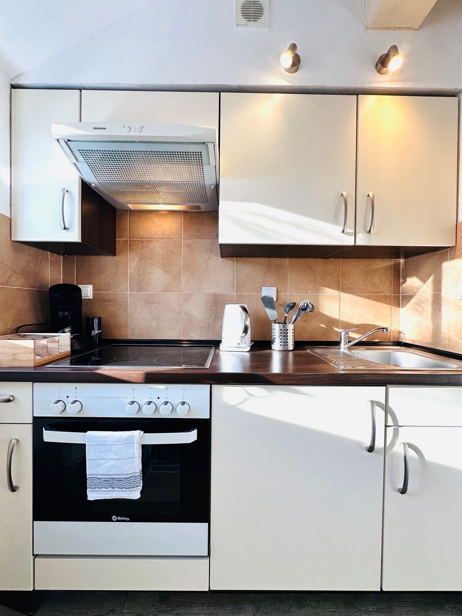 Una cocina moderna con horno empotrado, estufa, fregadero y campana extractora.
