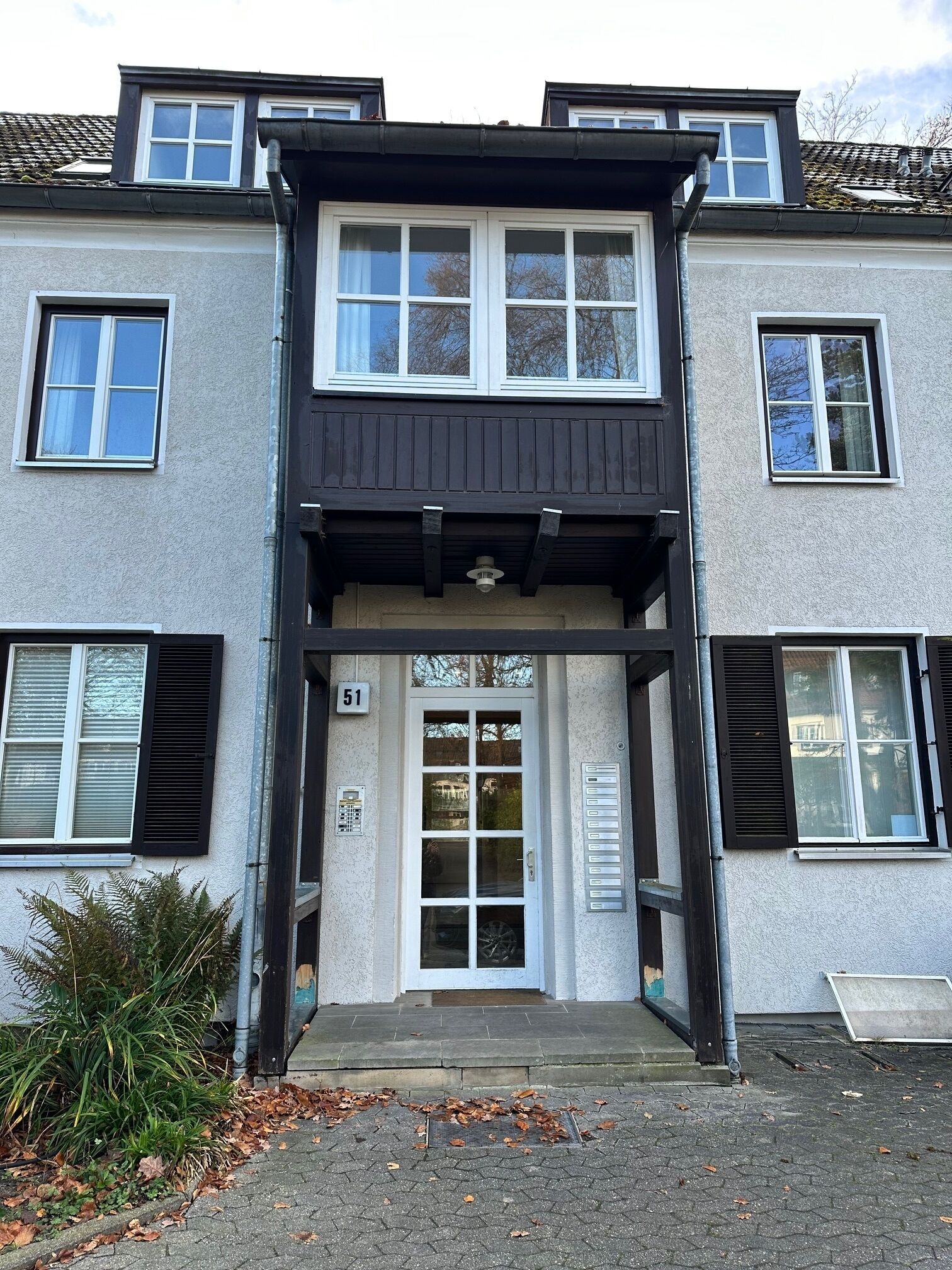A two-story building with a central entrance, a number '51' sign, and a small porch area.