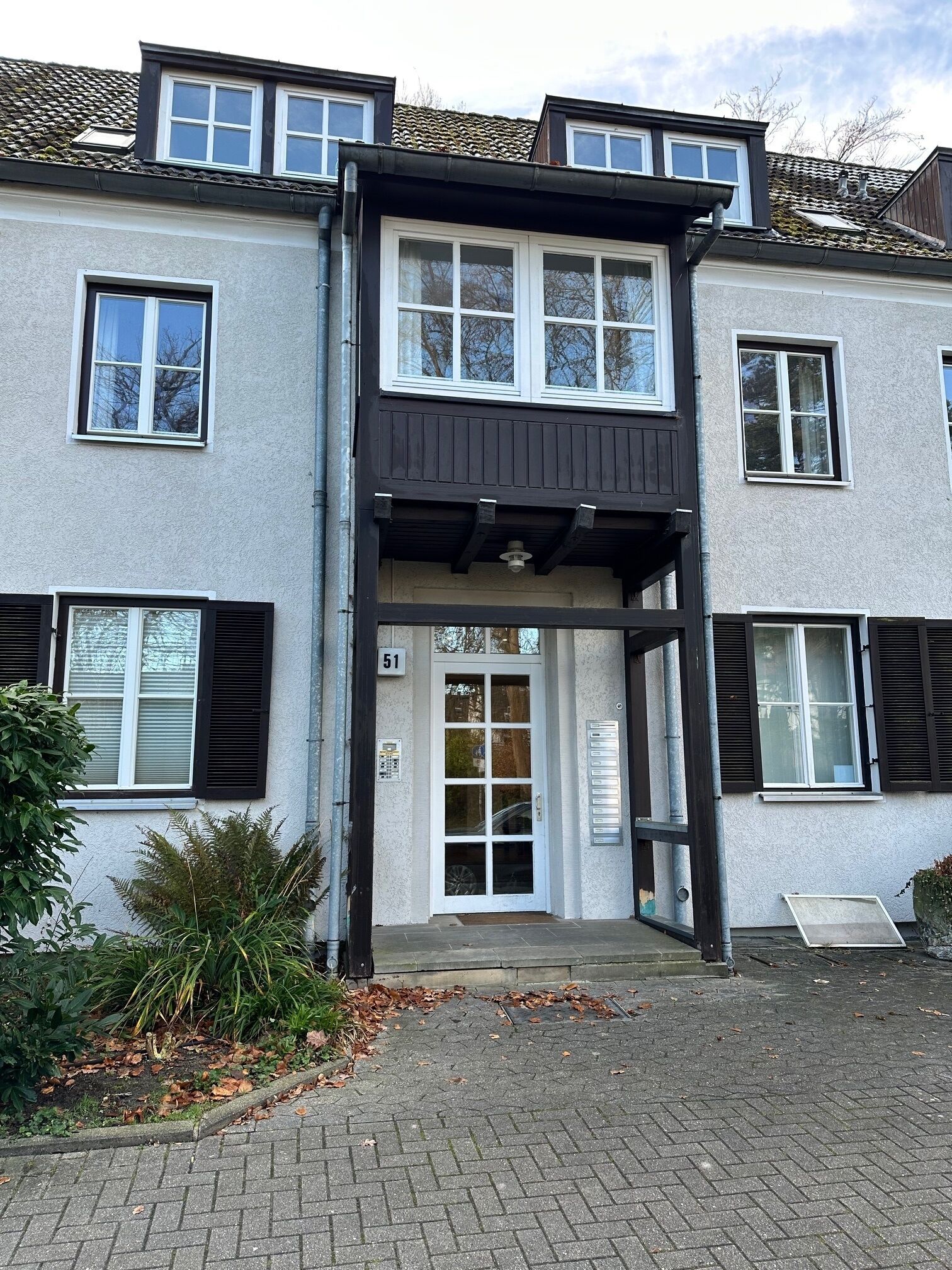 Ein zweistöckiges Gebäude mit einem mittleren Eingang, großen Fenstern und einem Schild mit der Nummer 51.